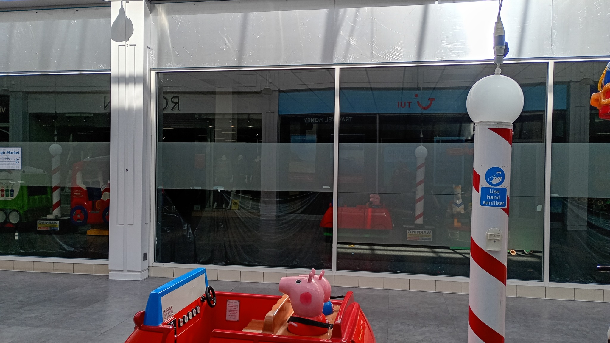 A closed shop with dark windows and shutters inside the shopping mall